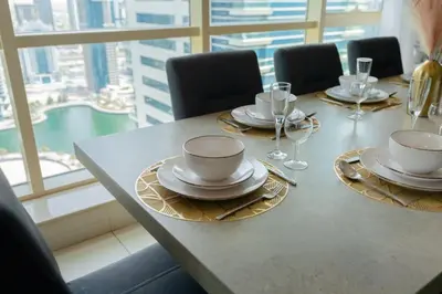 a table with plates and wine glasses on top of it at Royal Oceanic Elegant 2BR with Marina View in Dubai