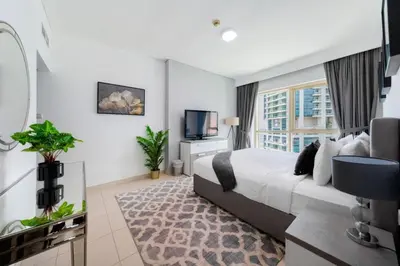 a bedroom with a large bed and a television at Royal Oceanic Elegant 2BR with Marina View in Dubai