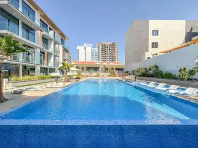 a large swimming pool with lounge chairs and a building at Luxurious Design Boutique Studio Hideaway JVC in Dubai