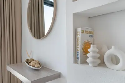 a mirror on a wall next to a shelf with vases at Luxurious Design Boutique Studio Hideaway JVC in Dubai
