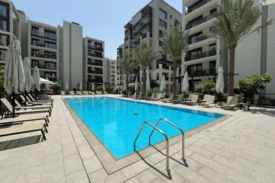 a swimming pool with chairs and umbrellas in a hotel at Vogue Creek Beach Rosewater Waterfront Living close to Downtown, Burj Khalifa and Dubai mall, Two Bedroom Apartment with Balcony and Vibrant Community View, Private Manmade Beach, Access to all Amenities in Sabkhah