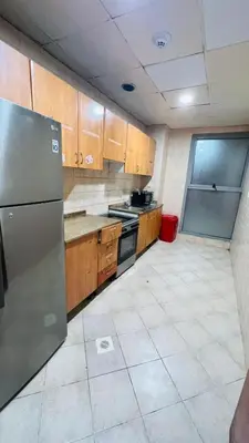a kitchen with wooden cabinets and a stainless steel refrigerator at Pleasing Partition Room Barsha Heights tecom in Dubai