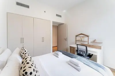 a white bedroom with a bed and a desk at DAYF-PAR Large 3 Bed with Full Skyline View in Dubai Hills in Dubai
