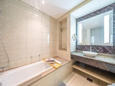 a bathroom with a tub and a sink and a mirror at Luxurious paramount 2BR with Pool,Gym, Sauna & Bar 10 mins to Burj Khalifa in Dubai