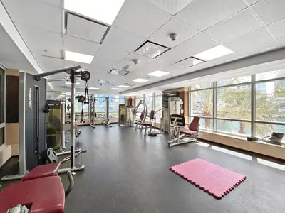 a gym with cardio equipment and red chairs and windows at VayK - Chic 1BR with Marina View in Park Island in Dubai
