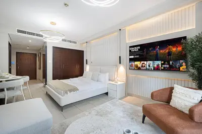 a bedroom with a bed and a tv on a wall at Chic Studio Apartment, Pool and Balcony, Steps to Burj Khalifa in Dubai