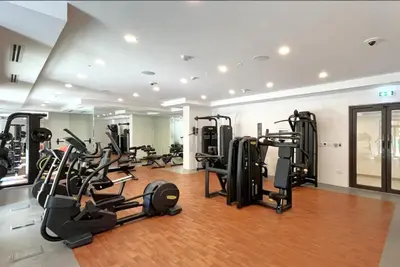 a gym with several treadmills and elliptical machines at Spacious 1BD, City View, Pool & Beach access in Dubai