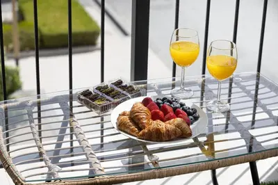 a glass table with a plate of food and two glasses of orange juice at Stylish Apartment - Private Beach - Port de La Mer in Dubai