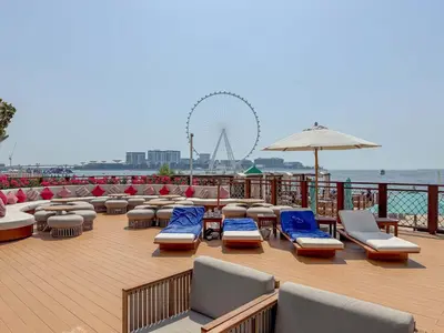 a deck with lounge chairs and an umbrella and a beach at Jumeirah Beach Residences Private Beach & Sea View in Dubai