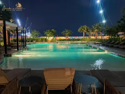 a large swimming pool at night with chairs and tables at Serene Canal View 2Bhk 6 pax in Dubai