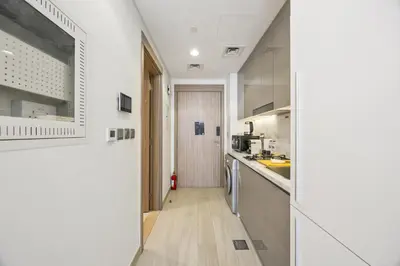 a kitchen with white walls and wooden floors and a hallway at Elite Escape - Getaway in Azizi Riviera 13 in Dubai
