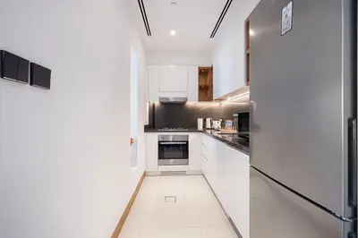 a kitchen with white cabinets and a refrigerator at Vida Yacht Club Marina 2BDR Sky Suite in Dubai