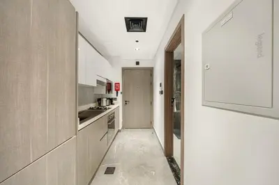a kitchen with white cabinets and a hallway at Dubai Arjan Studio - Near Miracle Garden, Hills Mall & Attractions in Dubai