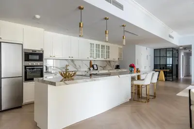 a kitchen with white cabinets and a large island at High-End Designer Stay l 4 Bed + Maids Room l JBR in Dubai