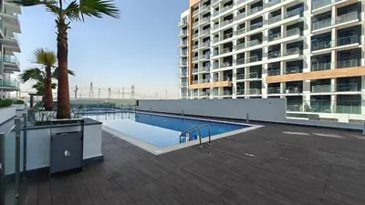 a swimming pool with a palm tree and a building at AirDXB - Chic Studio Apartment in Meydan Sleeps 2 with Balcony in Dubai