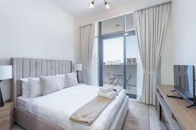 a bedroom with a large bed and a television at AirDXB - Chic Studio Apartment in Meydan Sleeps 2 with Balcony in Dubai