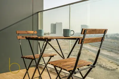 a wooden table and two chairs on a balcony at Bookable - Alexis Tower, Studio Room with Balcony in Dubai