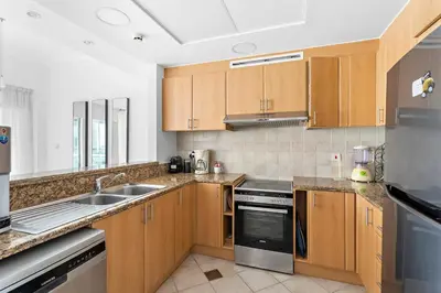 a kitchen with wooden cabinets and stainless steel appliances at Sleek and Spacious 2BR at Dubai Marina, Near Beach in Dubai