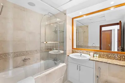 a bathroom with a tub and a sink and a mirror at Sleek and Spacious 2BR at Dubai Marina, Near Beach in Dubai