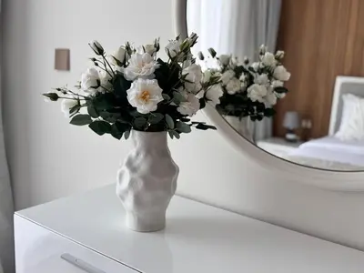 a vase with white flowers on a table in front of a mirror at 3BR Luxury Townhouse with Garden in Dubai