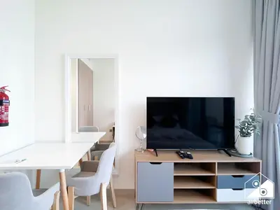 a living room with a television on a wooden entertainment center at Serenity Studio with Balcony at Azizi Riviera in Dubai