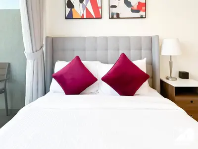 a white bed with two pink pillows on it at Modern Comfort Studio Relax & Unwind in Style in Dubai