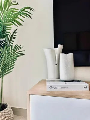a table with vases and a green plant on it at Citylight 1br Escape Gym, Pool And Free Parking! in Dubai