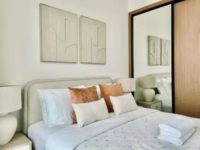 a bedroom with a bed with pillows and a mirror at Citylight 1br Escape Gym, Pool And Free Parking! in Dubai