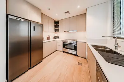 a kitchen with a stainless steel refrigerator and wooden floors at Spacious 3BD apartment at Creek Beach, Dubai in Dubai