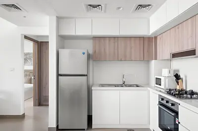 a white kitchen with a refrigerator and a sink at VayK - Large 1BR Near Hospital and Mall in Dubai