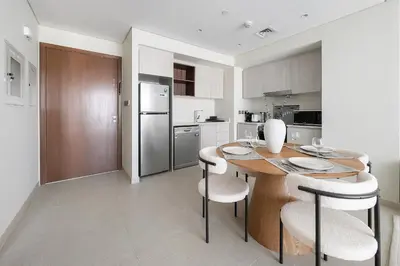 a kitchen with a wooden table and white chairs at VayK - Classy 1BR Near the Lagoon in Creek Harbour in Dubai