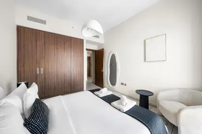 a bedroom with a large white bed and a chair at VayK - Classy 1BR Near the Lagoon in Creek Harbour in Dubai