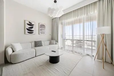 a white living room with a couch and a table at VayK - Classy 1BR Near the Lagoon in Creek Harbour in Dubai