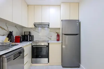 a kitchen with white cabinets and a stainless steel refrigerator at Upgraded 1BHK with Stunning Marina Views in Dubai
