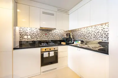 a kitchen with white cabinets and a stove at High-Floor Skyline View Near Safa Park and Godolphin Stables with Easy Access to Dubai Mall and Canal, Aykon City 2 Tower C, Business Bay by Deluxe Holiday Homes in Dubai