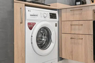 a washing machine in a kitchen with wooden cabinets at Enjoy Modern Comforts with Views of Burj Al Aráb and Nearby Attractions in Dubai