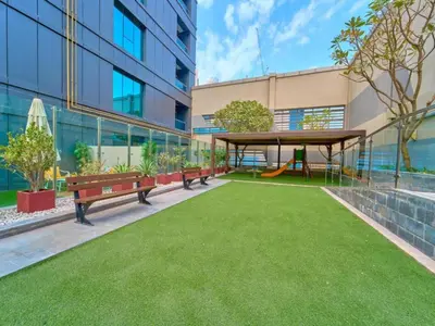 a park with benches and a playground in front of a building at Savis Homes - The Voleo - Bright and elegant studio - Business Bay in Dubai in Dubai
