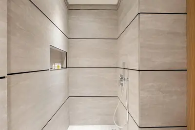 a bathroom with a wall with a shower stall at Stylish studio Near Downtown Dubai with Pool & Gym Access in Dubai
