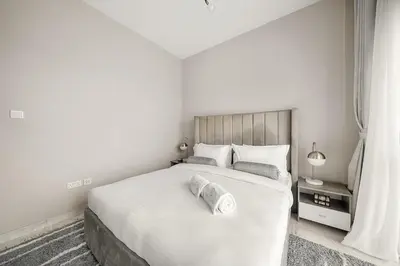 a white bedroom with a large bed and a window at FIRST CLASS 1BR Elegant Comfort Awaits in Dubai