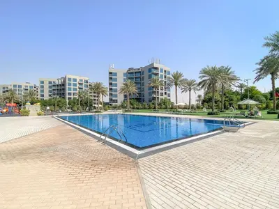 a large swimming pool with palm trees and buildings at FIRST CLASS 1BR Elegant Comfort Awaits in Dubai