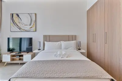 a bedroom with a large bed with two towels on it at Studio Apartment near Al Quoz Pond Park in Dubai