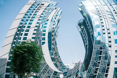 a tall glass building with a tree in front of it at Luxury Studio l Rooftop Pool & Gym Access in Dubai