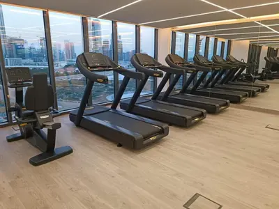 a row of treadmills in a gym with windows at Cozy Haven High Rise Balcony and Upscale Furnished in Dubai