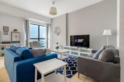 a living room with two blue couches and a tv at Spacious 2BR Flat with Gym & Pool in JBR in Dubai