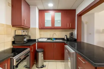 a kitchen with wooden cabinets and a sink and a counter at Spacious 2BR Flat with Gym & Pool in JBR in Dubai