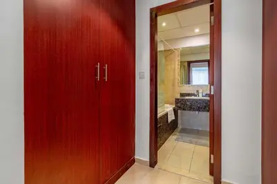 a hallway with red doors and a bathroom with a sink at Spacious 2BR Flat with Gym & Pool in JBR in Dubai