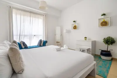 a white bedroom with a large white bed and a window at Spacious 2BR Flat with Gym & Pool in JBR in Dubai