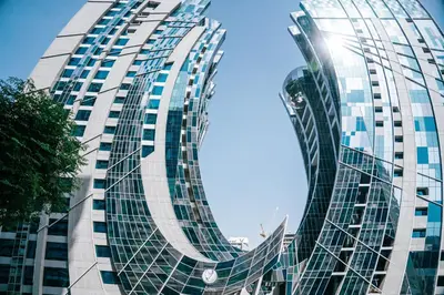 a tall glass building with the sun shining on it at Modern Studio in Business Bay l Pool, Gym & Sauna in Dubai