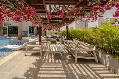a row of chairs under a pergola next to a pool at Vogue JVC Chaimaa Avenue near Circle Mall, One Bedroom Apartment with Balcony and City View, Access to all Amenities in Dubai