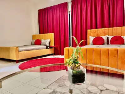 a living room with two beds and red curtains at Sandoval Gardens JVC in Dubai